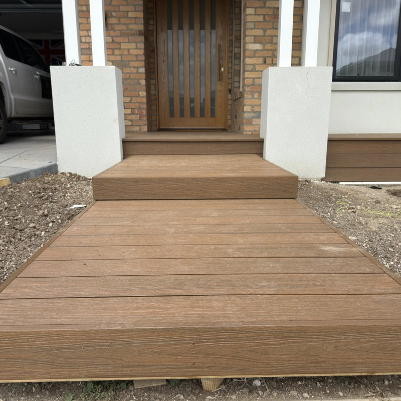 Timber decking path and step leading to a brick home's front door